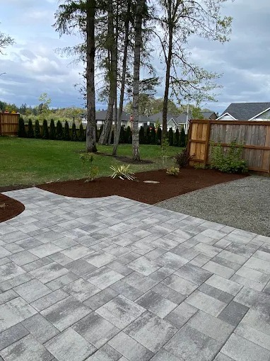 New gray paver patio bordered by fresh mulch planting beds